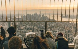 A crowd looking out at the NYC skyline from the top of a buliding